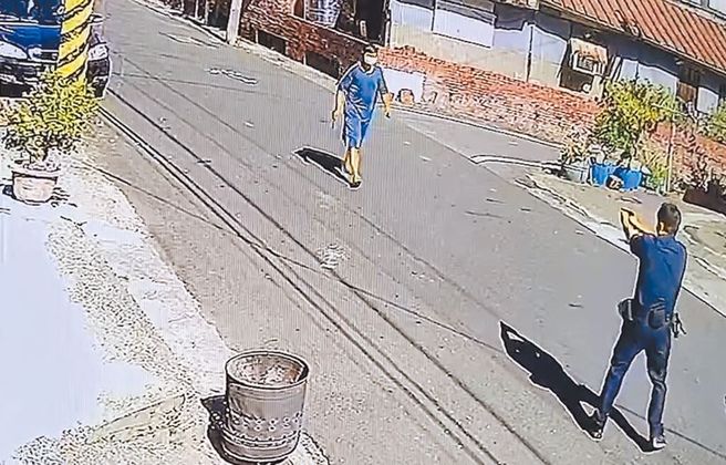 台南男挥舞双刀追逼袭警画面曝光。吴姓男子持双刀袭警，宅港派出所员警李峻安后退持枪对峙。（读者提供）