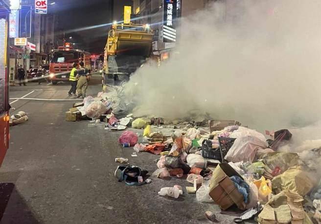 高雄三民区垃圾车清运垃圾时突起火燃烧，垃圾车驾驶急忙将垃圾倒在路面上喷水降温。（翻摄照片／崔正纲高雄传真）
