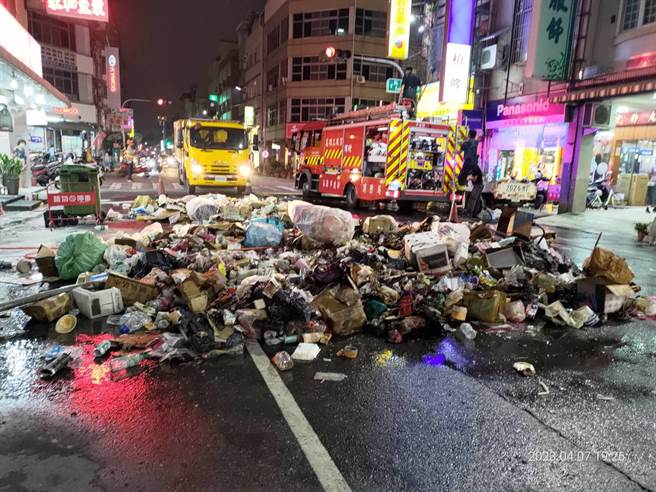 高雄三民区垃圾车清运垃圾时突起火燃烧，垃圾车驾驶急忙将垃圾倒在路面上喷水降温。（翻摄照片／崔正纲高雄传真）