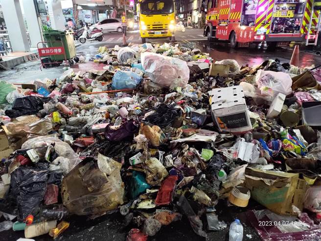 高雄三民区垃圾车清运垃圾时突起火燃烧，垃圾车驾驶急忙将垃圾倒在路面上喷水降温。（翻摄照片／崔正纲高雄传真）