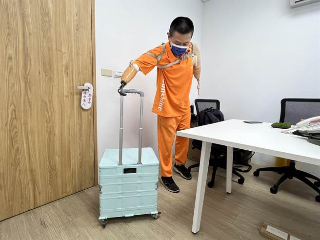 曾家玺因为截肢，无法撑伞只能穿雨衣，可能因此无法坐公车去上班，他就拖着一个小推车，把生活必需用品都放在里面。（李奇叡摄）