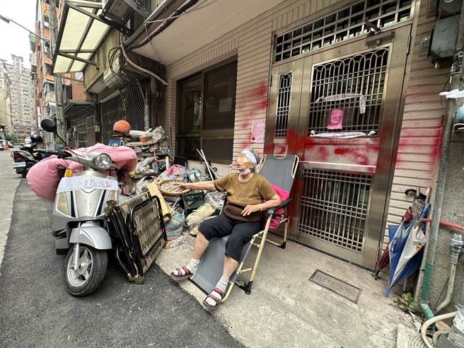 陳姓阿嬤守在門口不願意離開，阿嬤固執念舊令旁人心疼，最後在警方勸說下，跟家人一同離開。（讀者提供／張妍溱台中傳真）