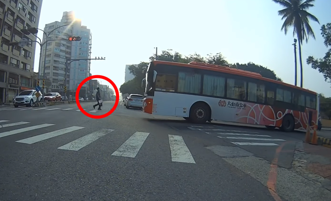 台南一輛公車13日綠燈右轉時，右側斑馬線上有名路人正從對面走過，公車司機連按3聲喇叭，催促對方通過，影片引發熱議。（翻攝自臉書「翻轉大台南交通違規2.0」）