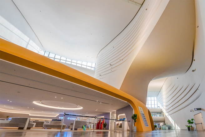 高雄港旅運中心內部空間挑高15米，灰白色圓弧牆面加上燈光點綴，散發著歌劇院般氛圍。(攝影/黃敬文)
