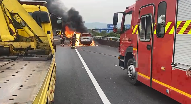 國1北上堤頂高架「火燒車」竄濃煙影響行車，車流回堵中。(警方提供)