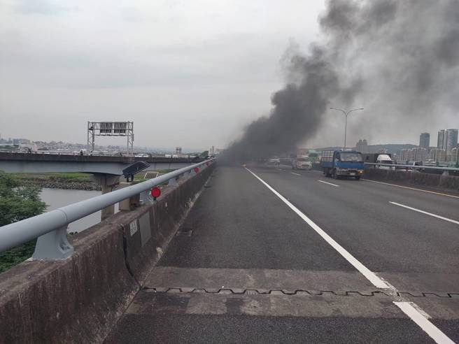 國1北上堤頂高架「火燒車」竄濃煙影響行車，車流回堵中。(警方提供)