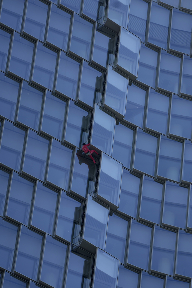 罗伯特未拉安全网、未穿戴安全吊带，徒手爬上38层楼。（图／美联社）