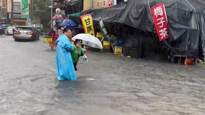 一名婦人在積水道路行走時跌倒，鹿港公所主祕洪誌誠見狀上前攙扶。（民眾提供／孫英哲彰化傳真）