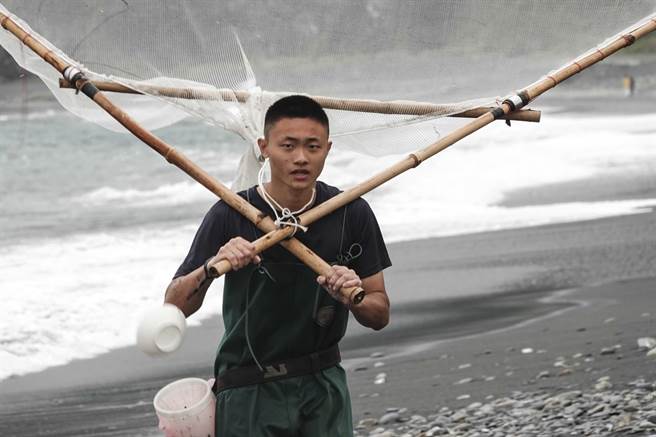 捕鱼苗少年背着三角网准备收工回家。（黄子明摄）