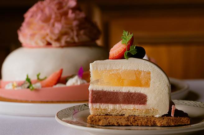 「白桃馨意-香槟白桃优格慕斯蛋糕」外观使用有巧克力界LV 的「Weiss Chocolate 白巧克力」，主厨将其手工捏制成逼真的康乃馨花。(劳瑞斯牛肋排餐厅提供)