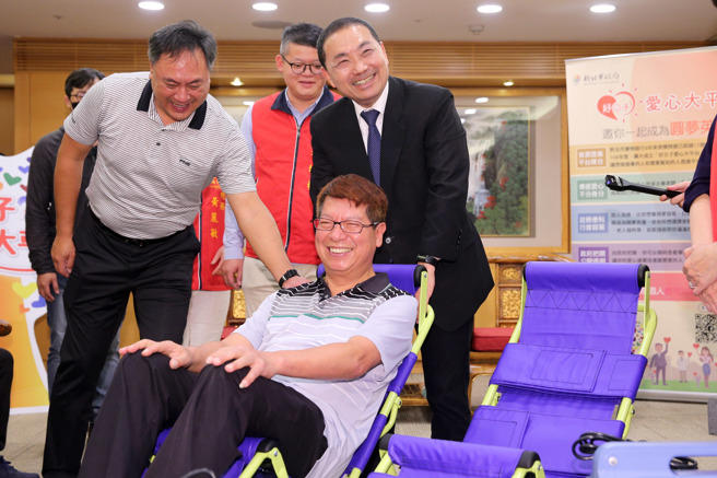 新北市长侯友宜（中）24日出席「李福田和芦洲復兴福德宫等捐赠爬梯机10台及制氧机60台」捐赠仪式，感谢他们造福新北市失能行动不便，及需要长期使用氧气维持生命的市民。侯友宜请捐赠者李福田（前）坐上爬梯机，亲自体验操作。（黄世麒摄）