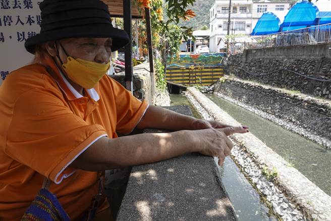 来义乡排湾族妇女温玉英坐在在二峰圳侧向溢流堰支流亲水区旁，监看民眾是否违反规定，她对维护这处族人重要水源命脉有强烈使命感。（黄子明摄）