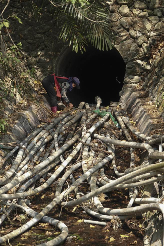 屏东来义乡新来义部落的罗姓老农妇发现田里无水可用，前往二峰圳主河道水管取水口查看并修復漏水水管。（黄子明摄）