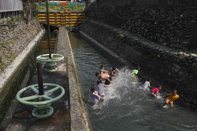 屏东来义乡二峰圳侧向溢流堰支流亲水区，水位虽然略为下降，仍有近40公分深度，足够让民眾泡水消暑。（黄子明摄）