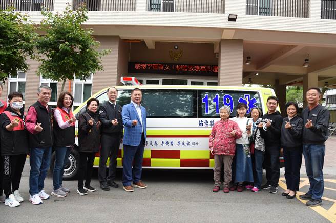 桃園85歲賣菜阿婆李黃香（右5）26日捐贈救護車給苗栗縣消防局，苗栗縣長鍾東錦特別到場致敬。（苗栗縣政府提供／謝明俊苗栗傳真）
