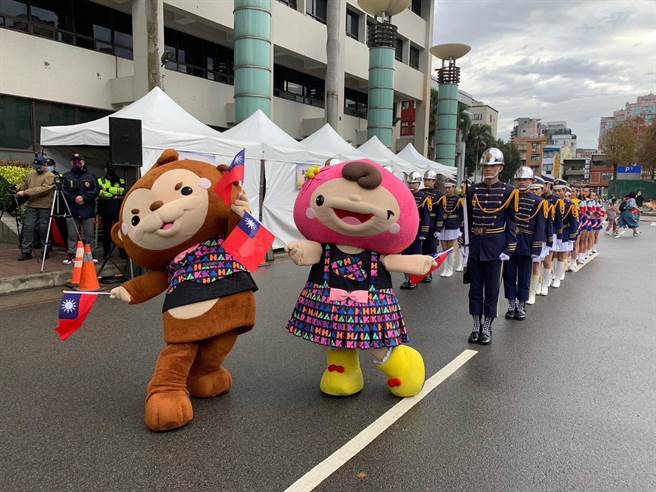 桃园吉祥物ㄚ桃、园哥元旦时穿着世客博主视觉图像的新衣，和民眾一起升旗。（蔡依珍摄）