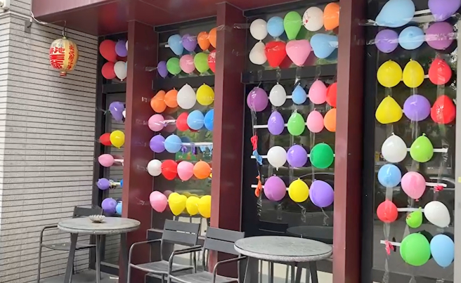 弘仁会绰号「乐乐」的大哥也在三重区娱乐公司外，摆放夜市的气球墙，并在道上放话呛声「有种来开枪啊！」。（黄敬文翻摄）