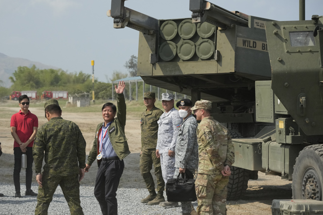 菲律宾总统马科斯（挥手者）蒞临美菲联合演习实弹射击现场，尷尬的是声名大噪的海马斯火箭炮（图右）却连６发全数脱靶。（图／美联社）