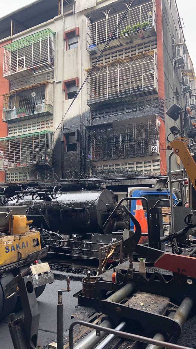 日前一辆沥青槽车在路上发生意外，车顶喷出大量沥青，导致一旁公寓墙壁、大门、窗户全被沥青覆盖「涂黑」，连工人抢修都被沥青淋全身。（翻摄自脸书「爆料公社」）