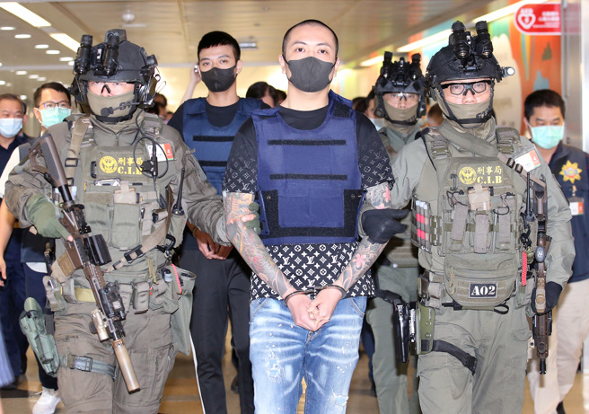 涉及土城槍擊案的林京履（前排中）及杜姓小弟（後）28日從馬來西亞押解回台，下機後兩人在刑事局除暴特勤隊員持MK18突擊步槍戒護下通關入境。（范揚光攝）