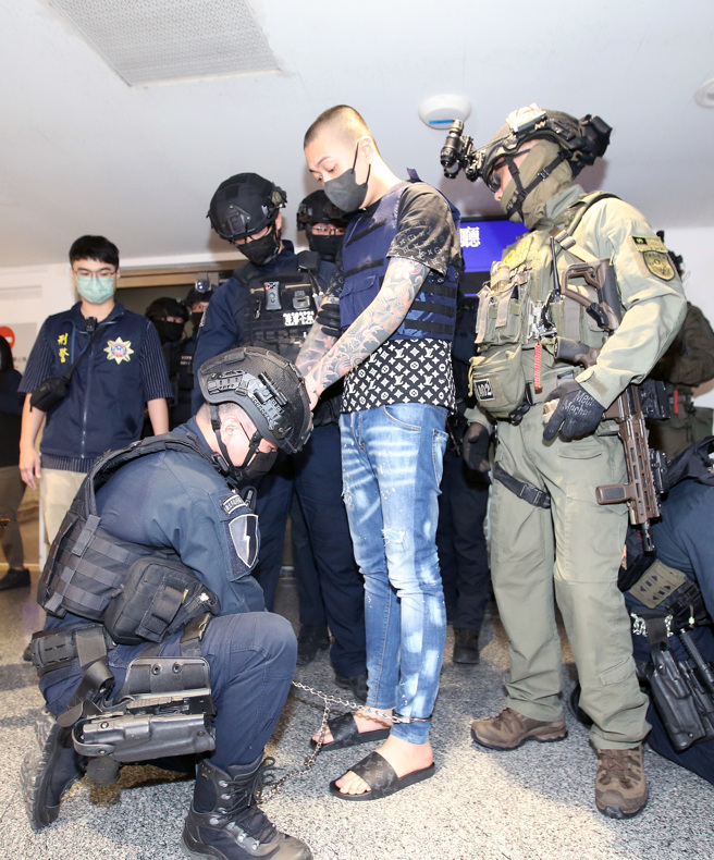 涉及土城槍擊案的林京履（中）28日從馬來西亞押解回台，新北市警局霹靂小組隊員為他鎖上腳鐐後帶回偵訊。（范揚光攝）