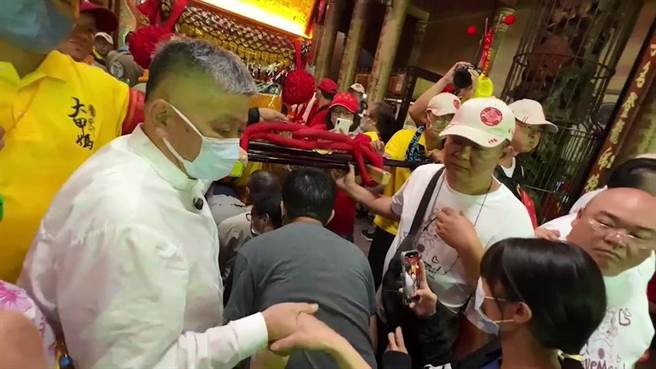 「标哥」站在轿前引导信眾钻轿脚，并与信眾握手致意。（孙英哲摄）