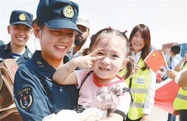 大陆从苏丹撤离中方人员部分乘包机返抵国门。图为在沙乌地吉达港，中国海军女兵护送一名撤离的儿童。（新华社）