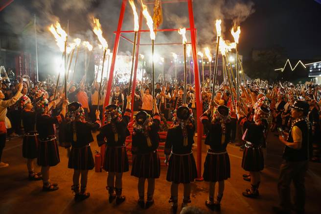 穿着云南少数民族服饰的妇女分持数十支火把进场，并把部分火把交给与会贵宾共同点燃篝火盆，熊熊烈火照亮现场。（黄子明摄）