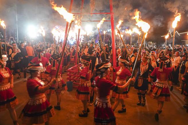 穿着云南少数民族服饰的妇女分持数十支火把进场，并把部分火把交给与会贵宾共同点燃篝火盆，熊熊烈火照亮现场。（黄子明摄）