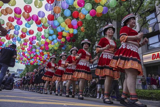妇女穿上各民族传统族服参加踩街活动，沿路边走边跳舞。（黄子明摄）