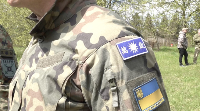 安德烈受访时别上自制「万岁」布徽章。（图/ 中央社）