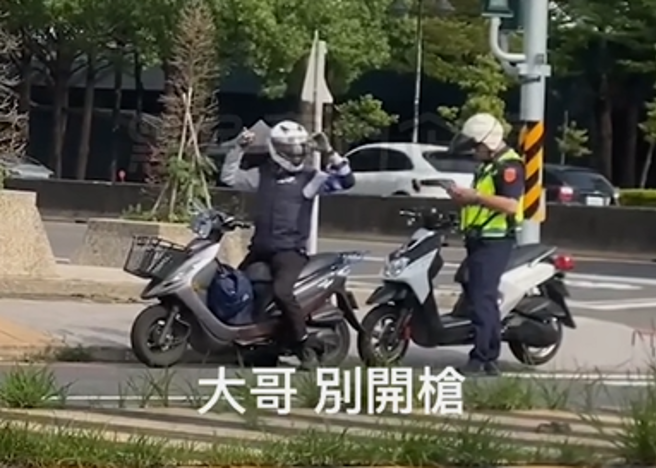 男機車騎士日前被攔檢時，被目擊高舉雙手，還不時轉動身體，當時警方在後方疑似準備開單，畫面曝光網友笑說「他一定是移民回來台灣居住的」。（翻攝自臉書「黑色豪門企業」）