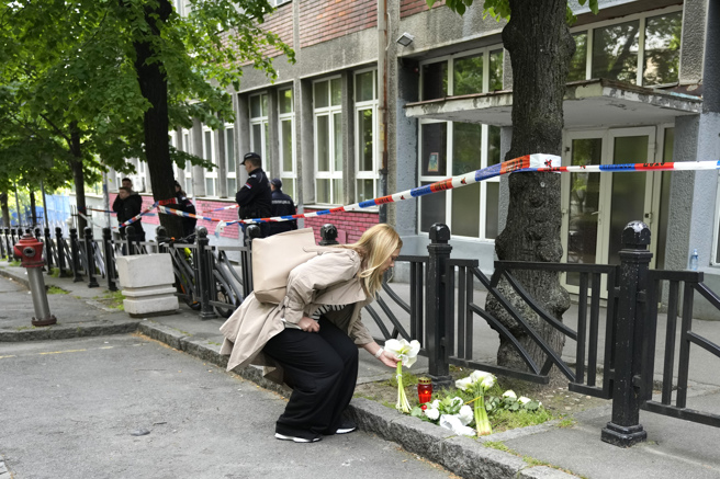 塞尔维亚首都一所小学3日发生大规模枪击案，震惊全国。有民眾陆续带着鲜花摆在校外哀悼。（图／美联社）