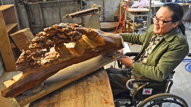 名木雕刻家林正發及其作品「母子情深」。(林正發工作室提供)