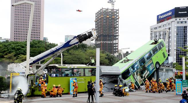 台北市政府民安9号演习，在溃缩车体脱困作业演练中，救难人员在变形的公车旁搜救受伤民眾。（郑任南摄）