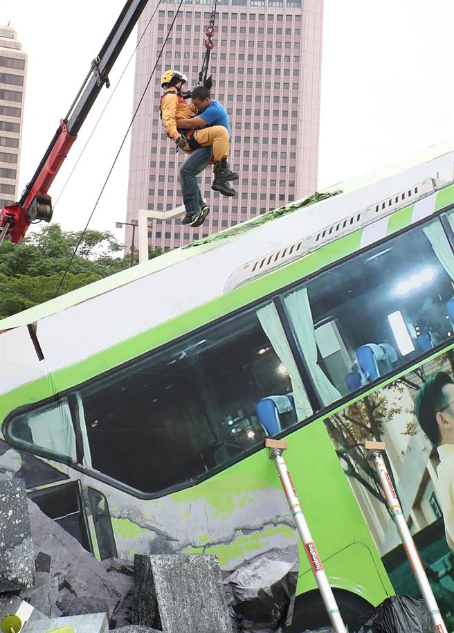 台北市民安9号演习，在溃缩车体脱困作业演练中，救难人员在变形的公车旁搜救受伤民眾。（郑任南摄）