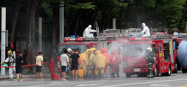 台北市民安9号演习，在战时毒性化学物质灾害抢救演练中，穿着防护衣的救难人员在灾害发生后抵达现场，将民眾带到由消防车组成的临时淋浴区给予水洗，降低化学物质毒性。（郑任南摄）