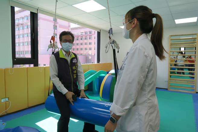 彰化县副县长林田富（左）体验彰化医院儿童復健的悬吊系统。（院方提供／孙英哲彰化传真）