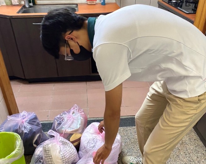 信义房屋民俗公园店黄昱昌协助客户整理回收衣物。（图/信义房屋 提供）