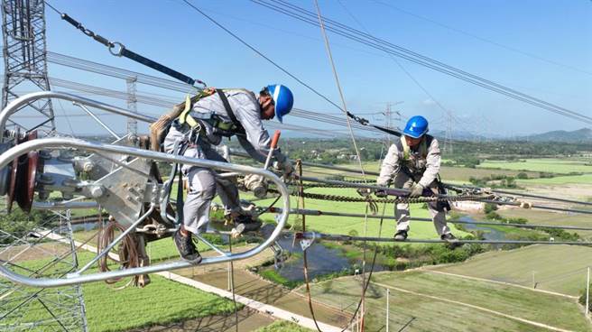 图为一名大陆电力工人正在攀爬铁塔进行电网高空作业。（摘自新华社）
