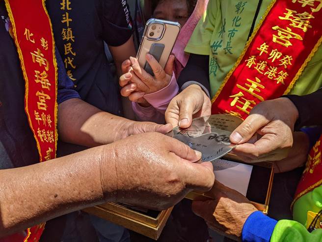 彰化南瑶宫与北斗中圳白鹤宫将各持一半的仿古银牌加以併拢、核对，完成对龙银仪式。（彰化市公所提供／孙英哲彰化传真）