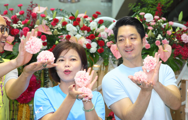 迎接母亲节，台北市长蒋万安（右）6日与国民党台北市议员游淑慧（中）等人出席台北花卉公司康乃馨推广活动，现场比出最近热门的「开花舞」手势。（张铠乙摄）