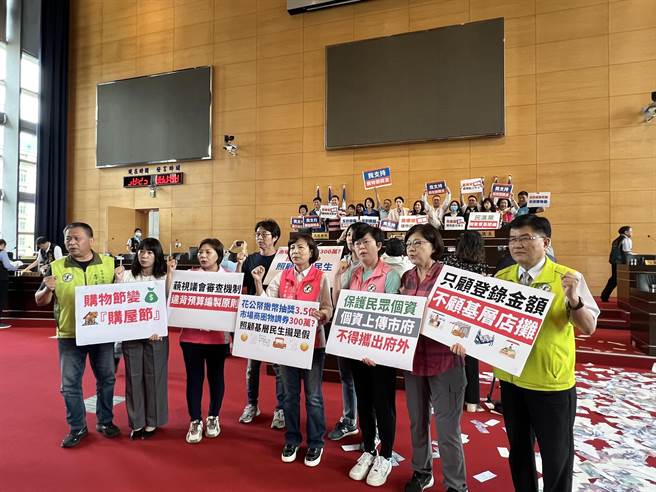 台中市议会为了购物节3.5追加预算，蓝、绿议员高举海报互呛。(林欣仪摄)
