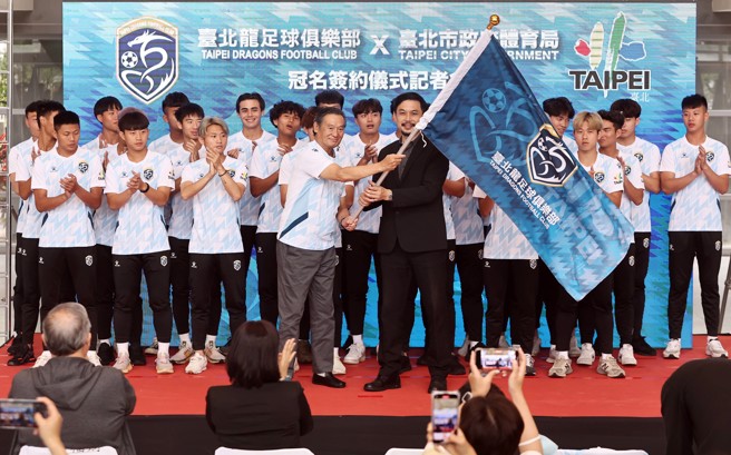 日籍教练今井敏明（前排左）与台北市体育局局长王泓翔（前排右）共同挥舞台北龙足球俱乐部队旗。（台湾运动文创提供）
