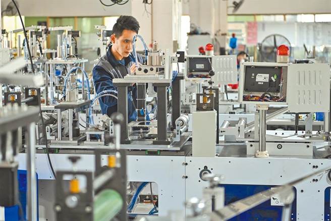 图为东莞快裕达自动化设备有限公司工作人员在生产线上组装口罩机。（中新社）