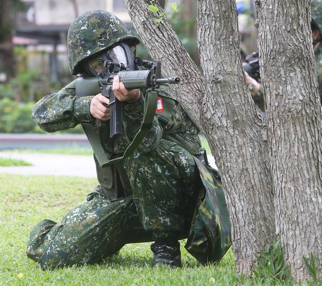国军首批志愿接受教育召集的14位女性后备军人，9日在桃园八德地区实施城镇战操练，实兵实装的女性官兵实作穿戴毒气面罩出枪试瞄科目。（陈怡诚摄）