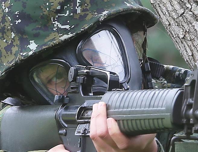 国军首批志愿接受教育召集的14位女性后备军人，9日在桃园八德地区实施城镇战操练，实兵实装的女性官兵实作穿戴毒气面罩出枪试瞄科目。（陈怡诚摄）