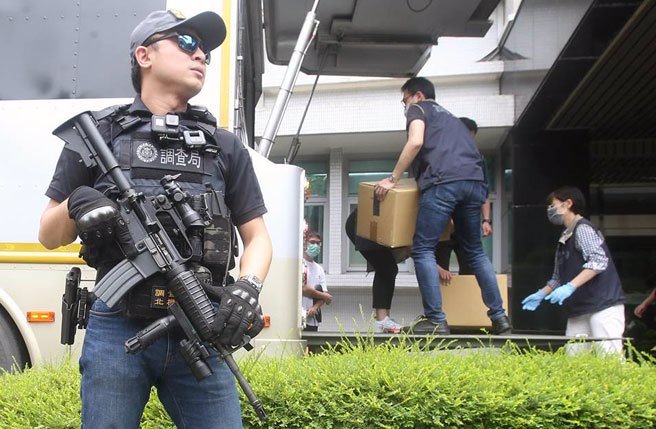 调查局举行全国获案毒品证物公开销燬仪式，调查人员将一箱箱的毒品搬上货车运往焚化炉，荷枪实弹的干员在一旁警戒。（范扬光摄）