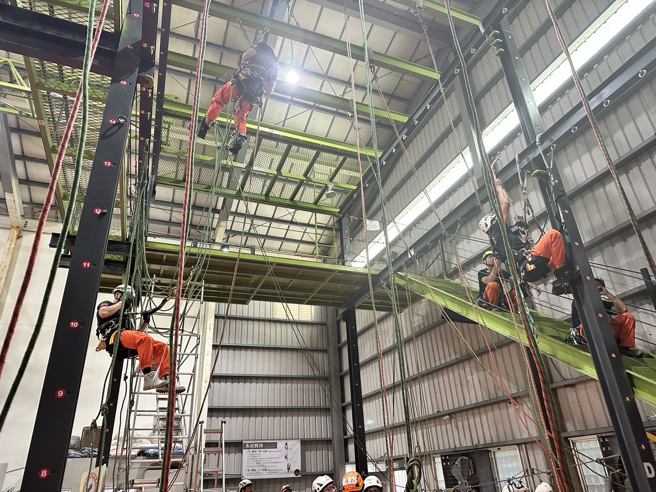 新北市内丰富的自然环境和公共设施成为了本次的天然训练场，从高楼建筑物、桥梁、多变的山域及地下设施等场域模拟救援任务，让学员在实战情境中熟练个人须掌握绳索技巧和操作方法及作战小组的分工与团队合作，进而提升救援效率。（图／消防局提供）