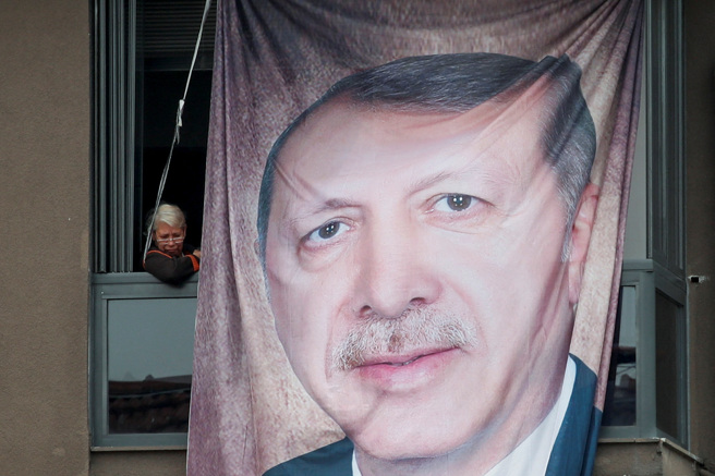 土耳其总统大选14日投票。土耳其西部大城布尔萨（Bursa）的居民，11日在一栋悬挂现任总统艾尔多安巨型竞选人像的大楼窗户旁观看在野党造势活动。（路透社）